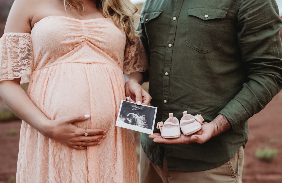 Ashley and Kevin holding their ultrasound and baby shoes