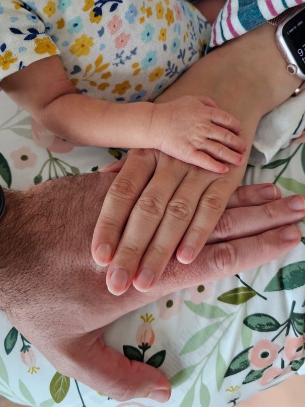 Baby's hand on top of Mom's hand on top of Dad's hand